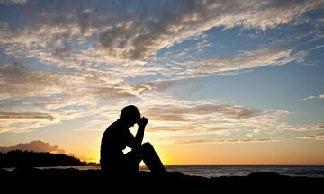 A woman deep in thought sitting by the sea. Prayer.