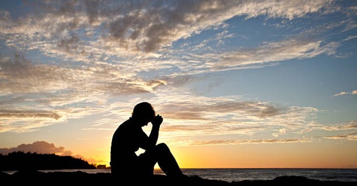 A woman deep in thought sitting by the sea. Prayer.