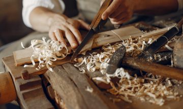 Man working with a wood. Carpenter in a white shirt