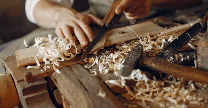 Man working with a wood. Carpenter in a white shirt